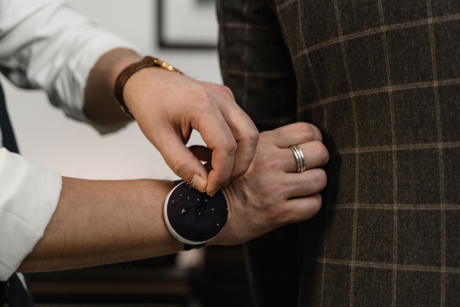 A tailor carefully fitting a suit sleeve; representative tailoring photography